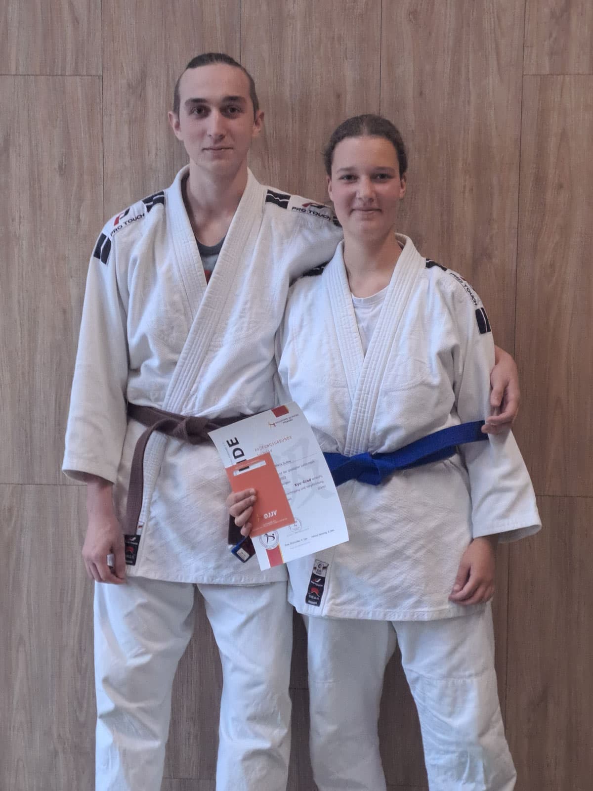 Zwei Ju-Jutsuka im Anzug mit Prüfungsurkunde nach der Kyu-Prüfung